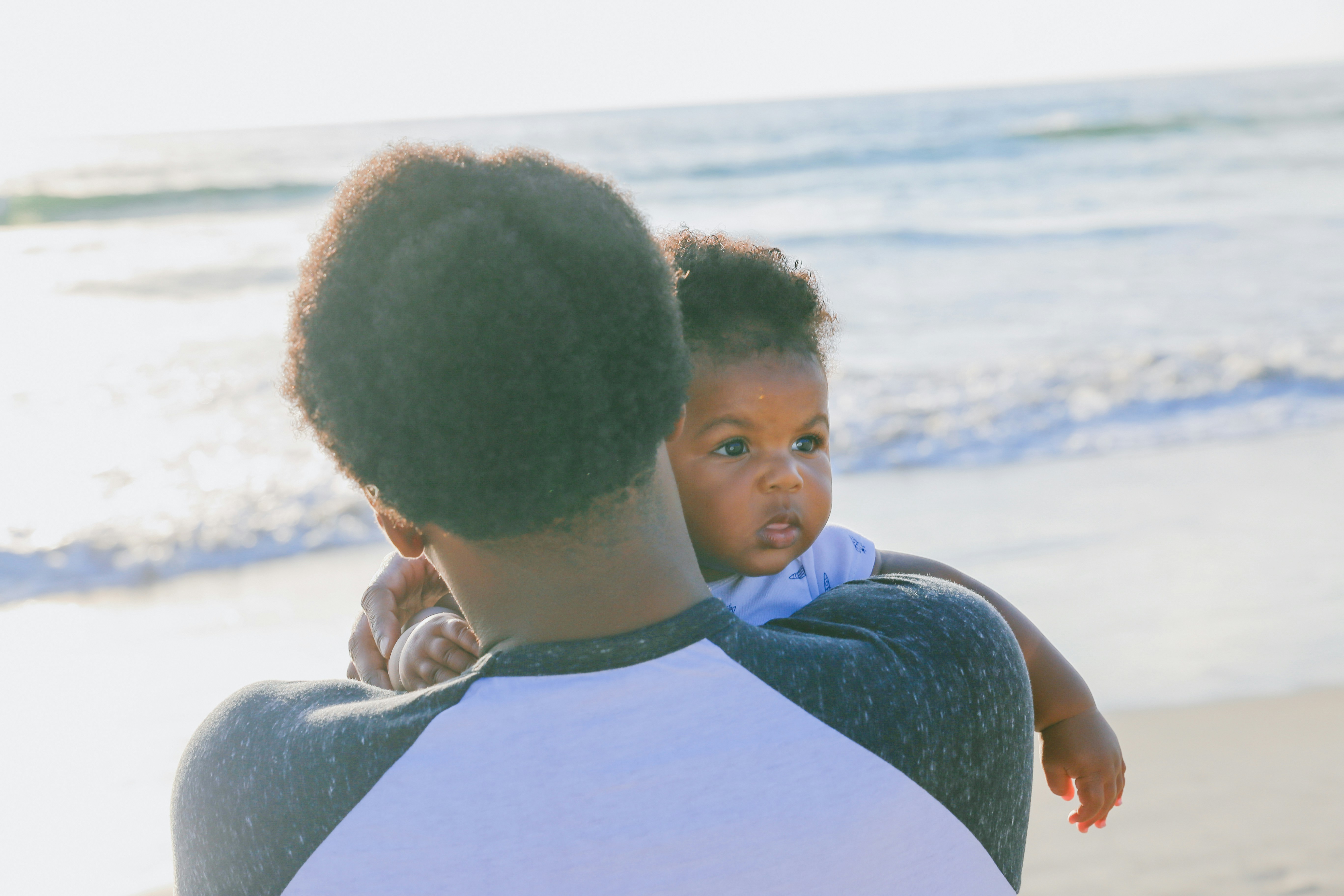 Candid seaside photo of a dad and son bonding, showing love, hope, connection, and representation.